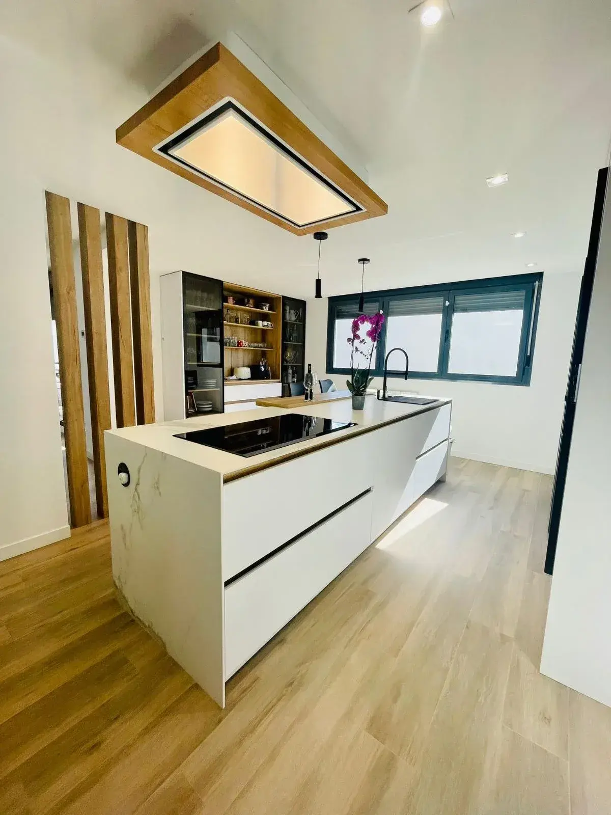 La misma cocina ya montada, blanca con campana de madera al techo