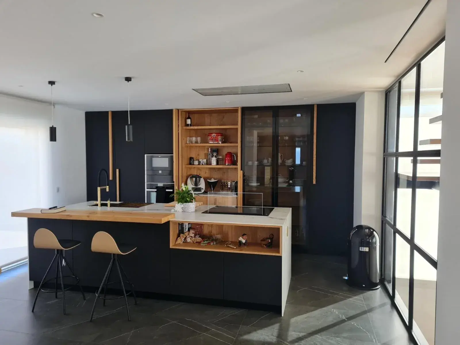 La misma cocina ya montada, en negro mate con isla y barra de roble